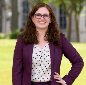 Carrie Murawski standing in front of a grassy hill with their hand on their hip.